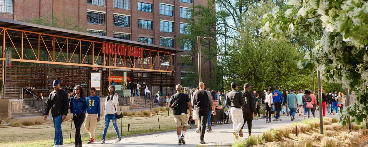 A picture of Ponce City Marker with a large group of people walking in both directions on the Beltline trail in front of it