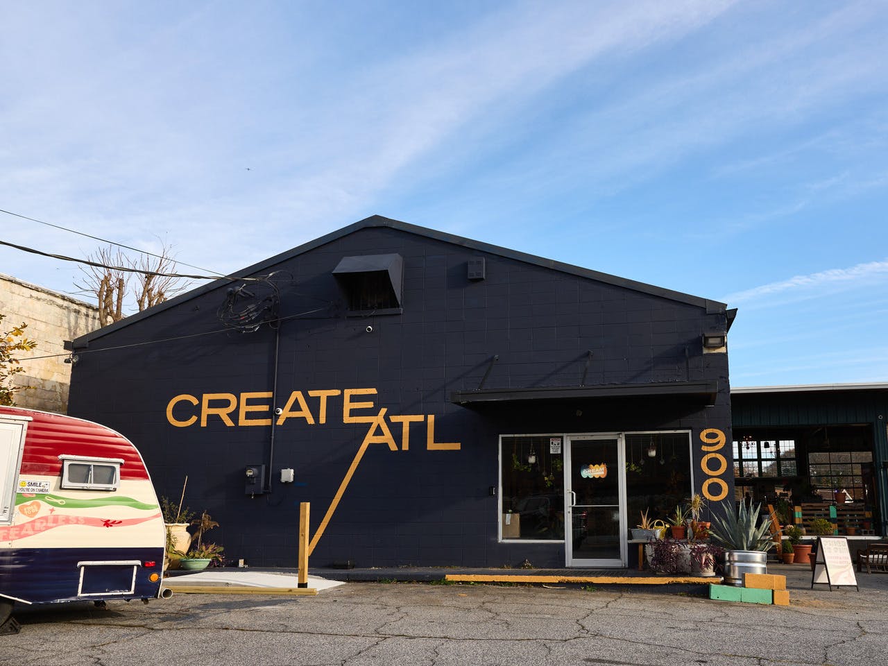The outside of a building is painted a sharp black with bold yellow reading "Create ATL."