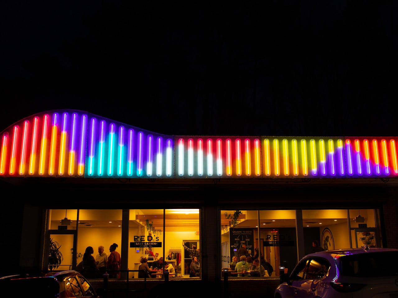The exterior of a building at night that has colorful lights in a whimsical pattern above it.