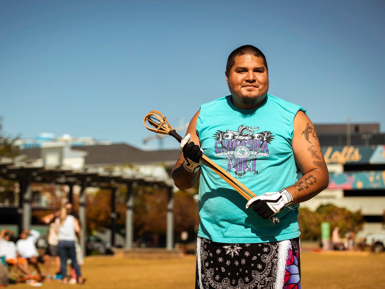 A person stands, holding a toli stick and smiling for the camera.