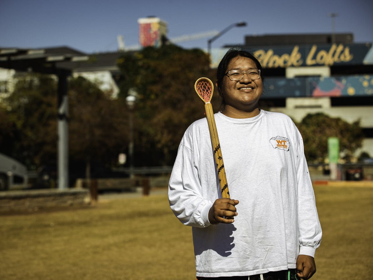 A person stands, holding a toli stick and smiling for the camera.