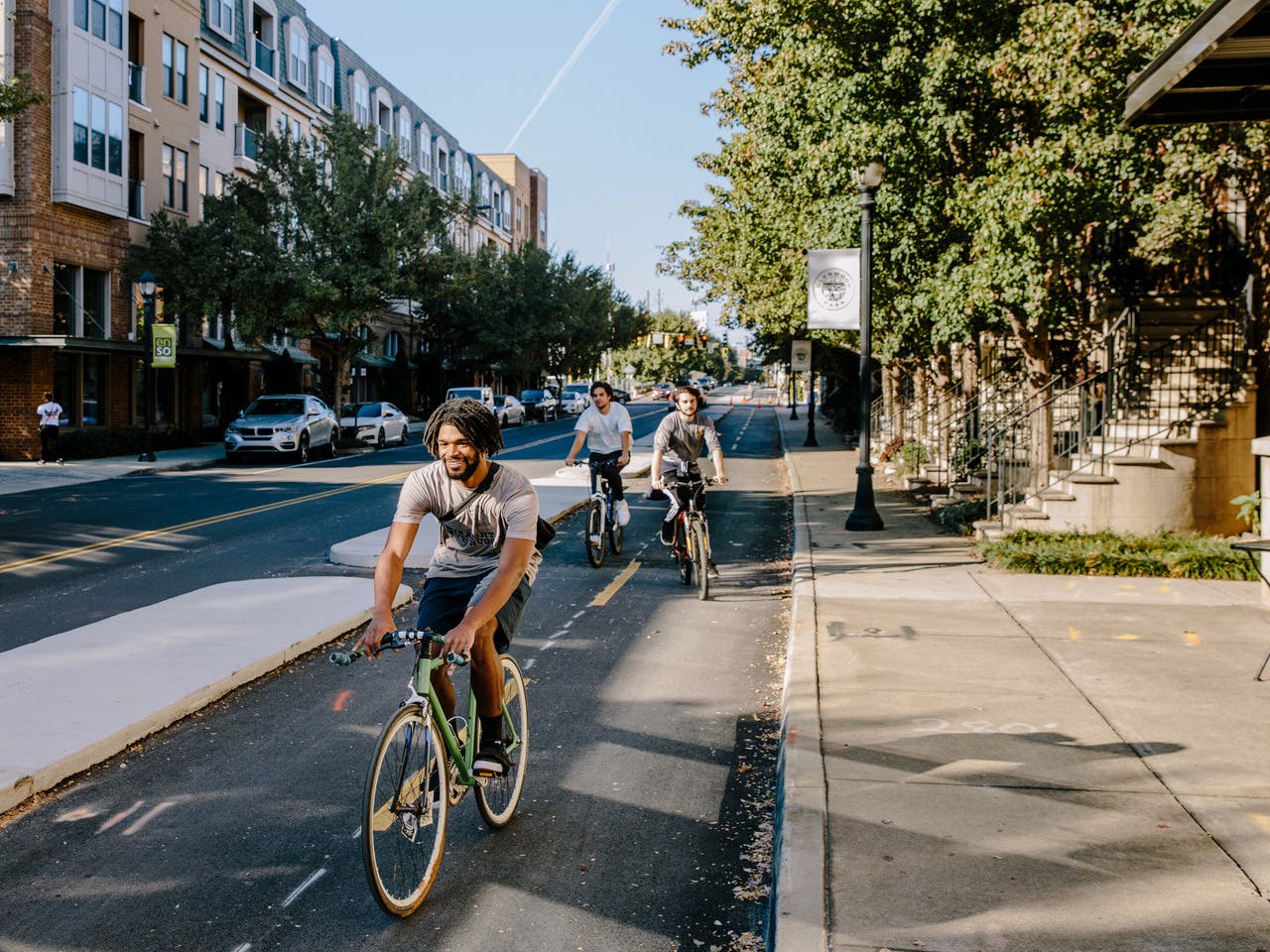 A group of people bike in a designated trail space next to the road.