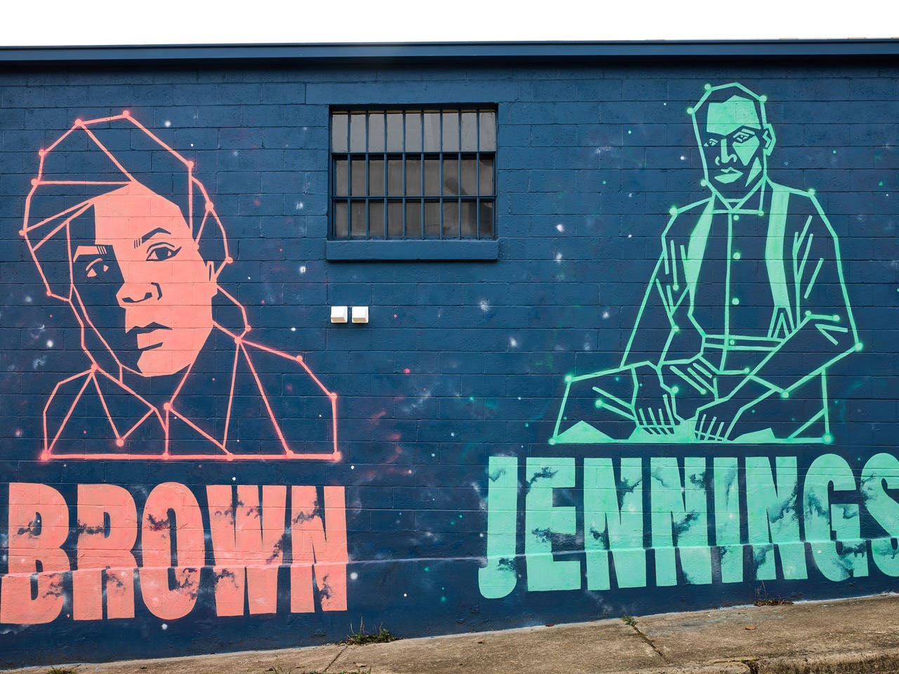 A mural depicts two black inventors and entrepreneurs on a blue exterior wall.