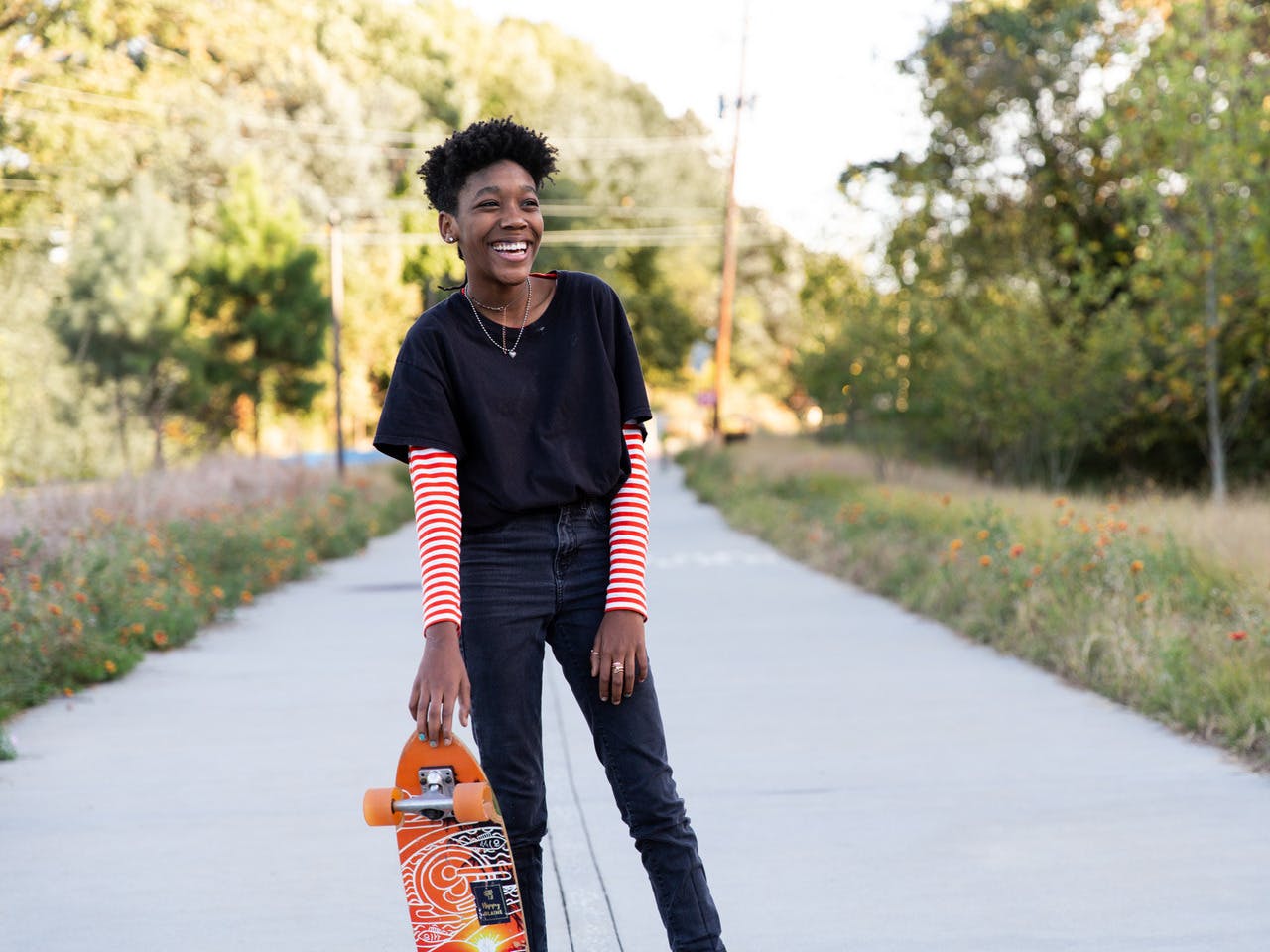 A person holds a skateboard and laughs.