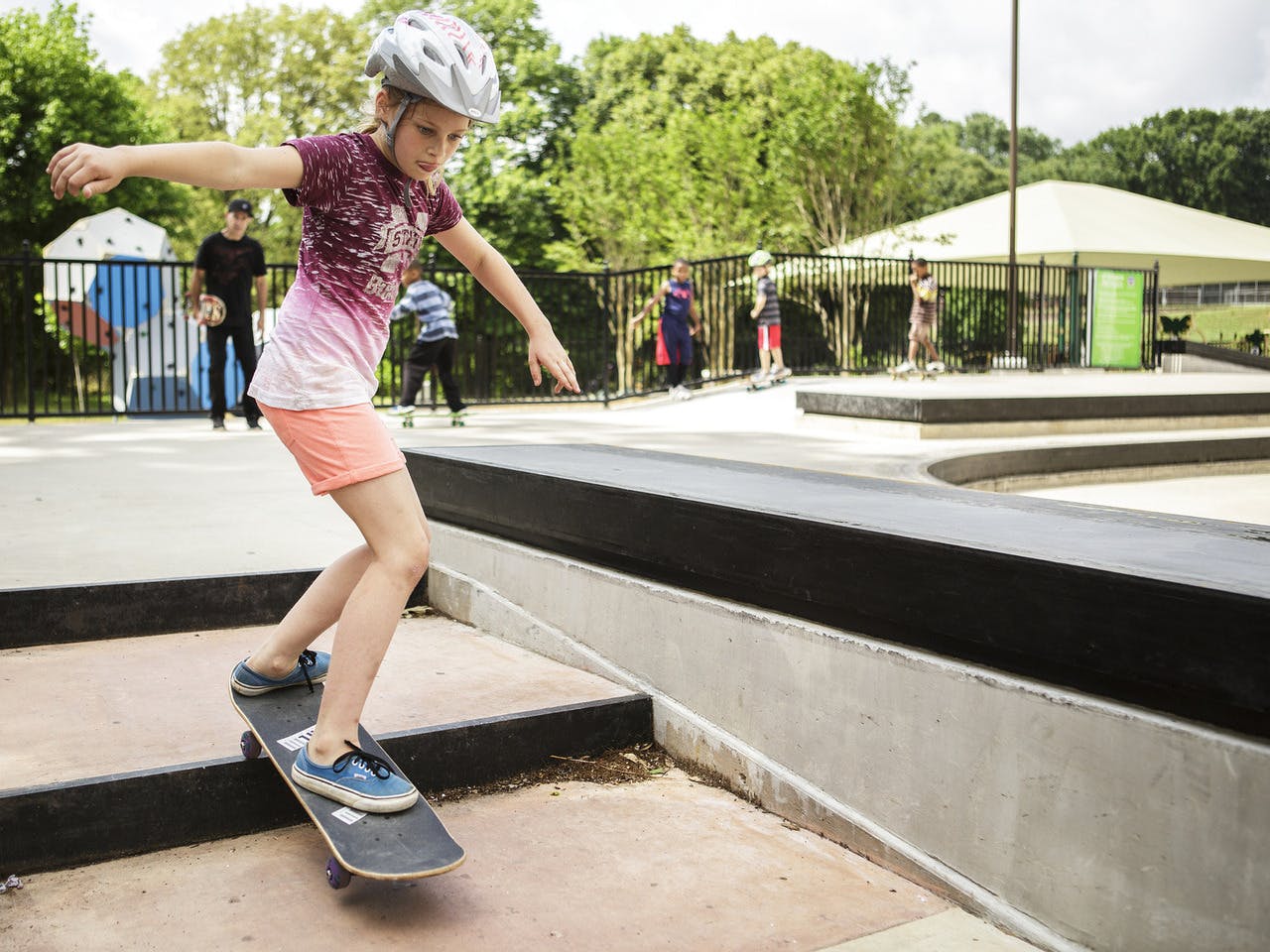 A girl skates down stairs at skatepark.