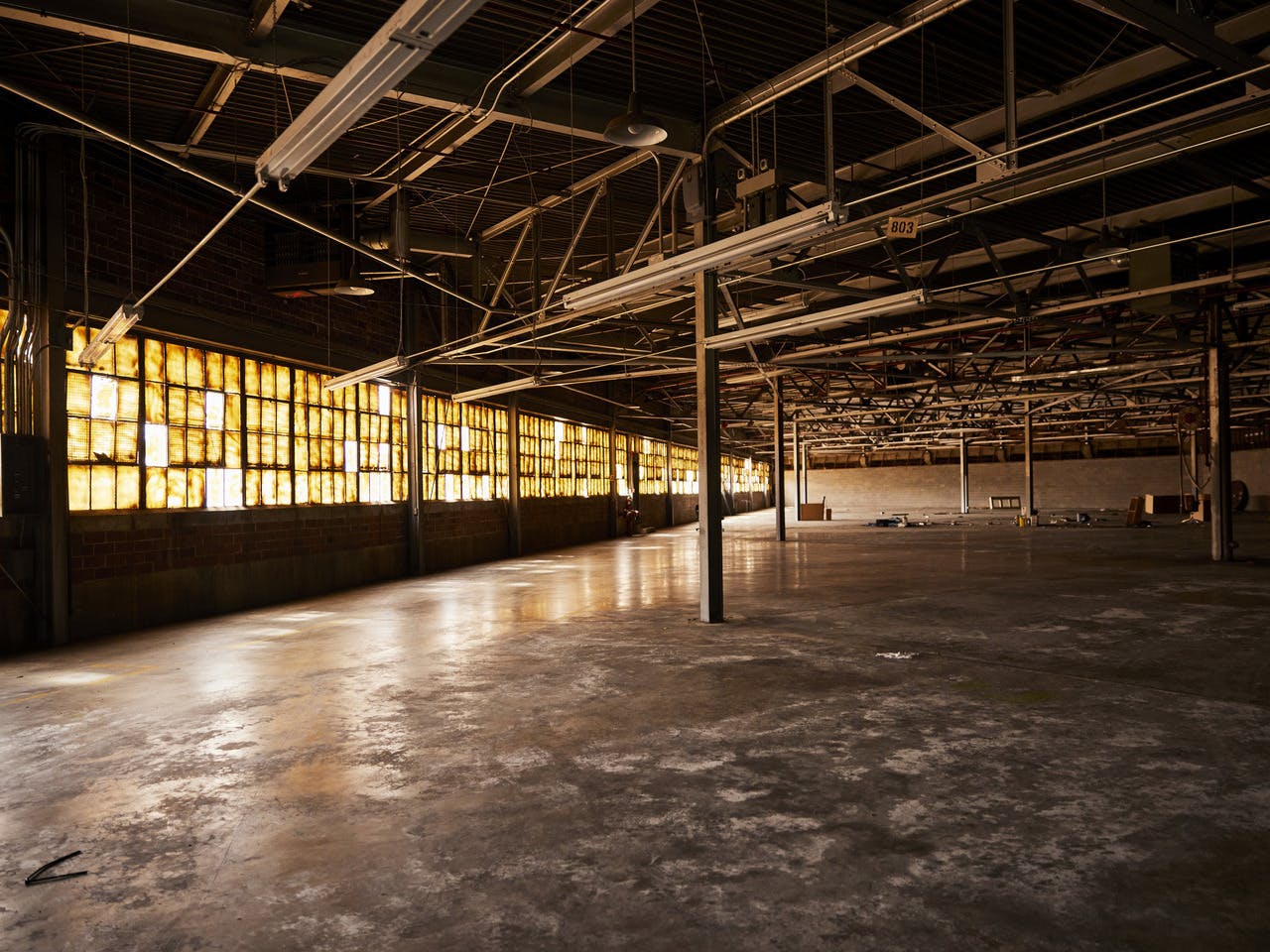 The inside of an abandoned warehouse with sun spilling in the broken windows.