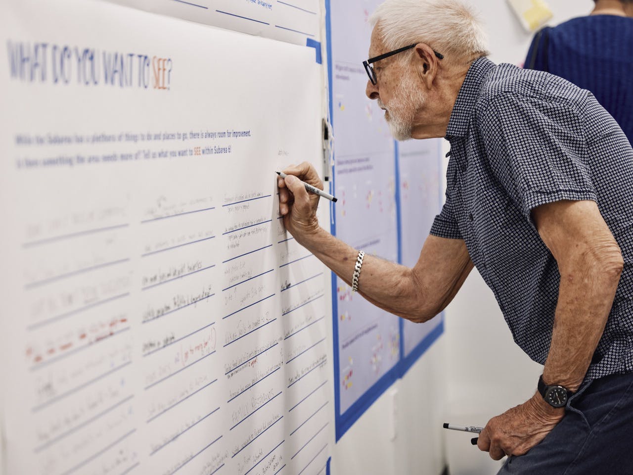 An older man writes what he wants to see on the Atlanta Beltline on a large poster.