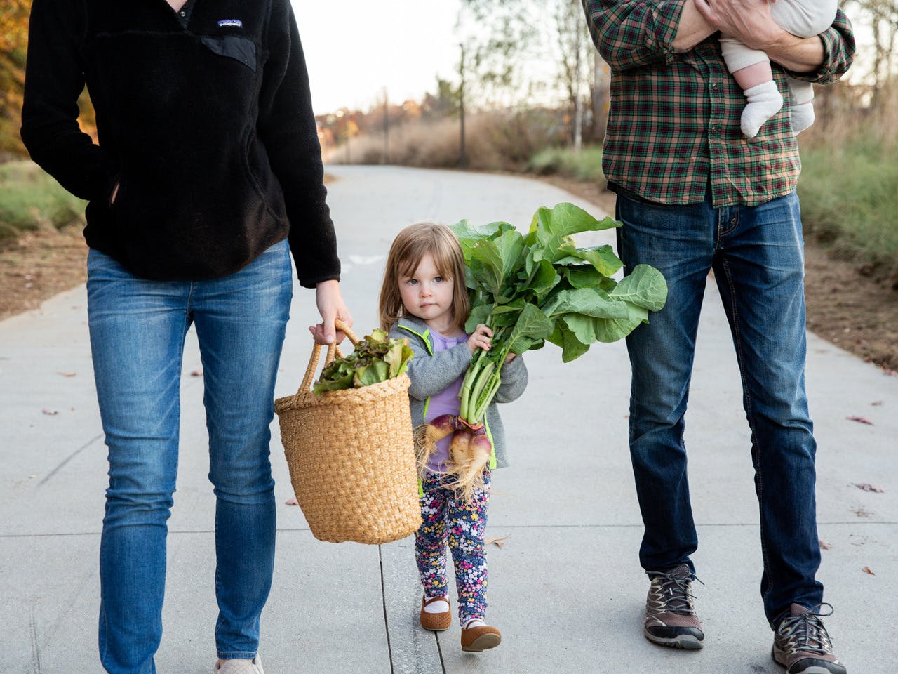A family walks along the Westside Trail with fresh produce.