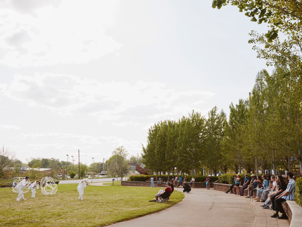 A dance performance take place in a park while people watch.