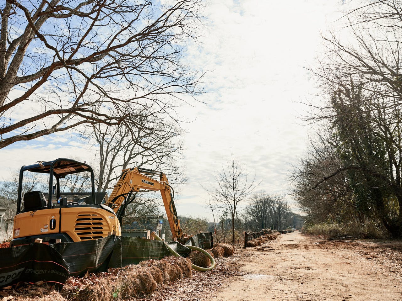 A large piece of construction equipment sits to the right of a dirt path.