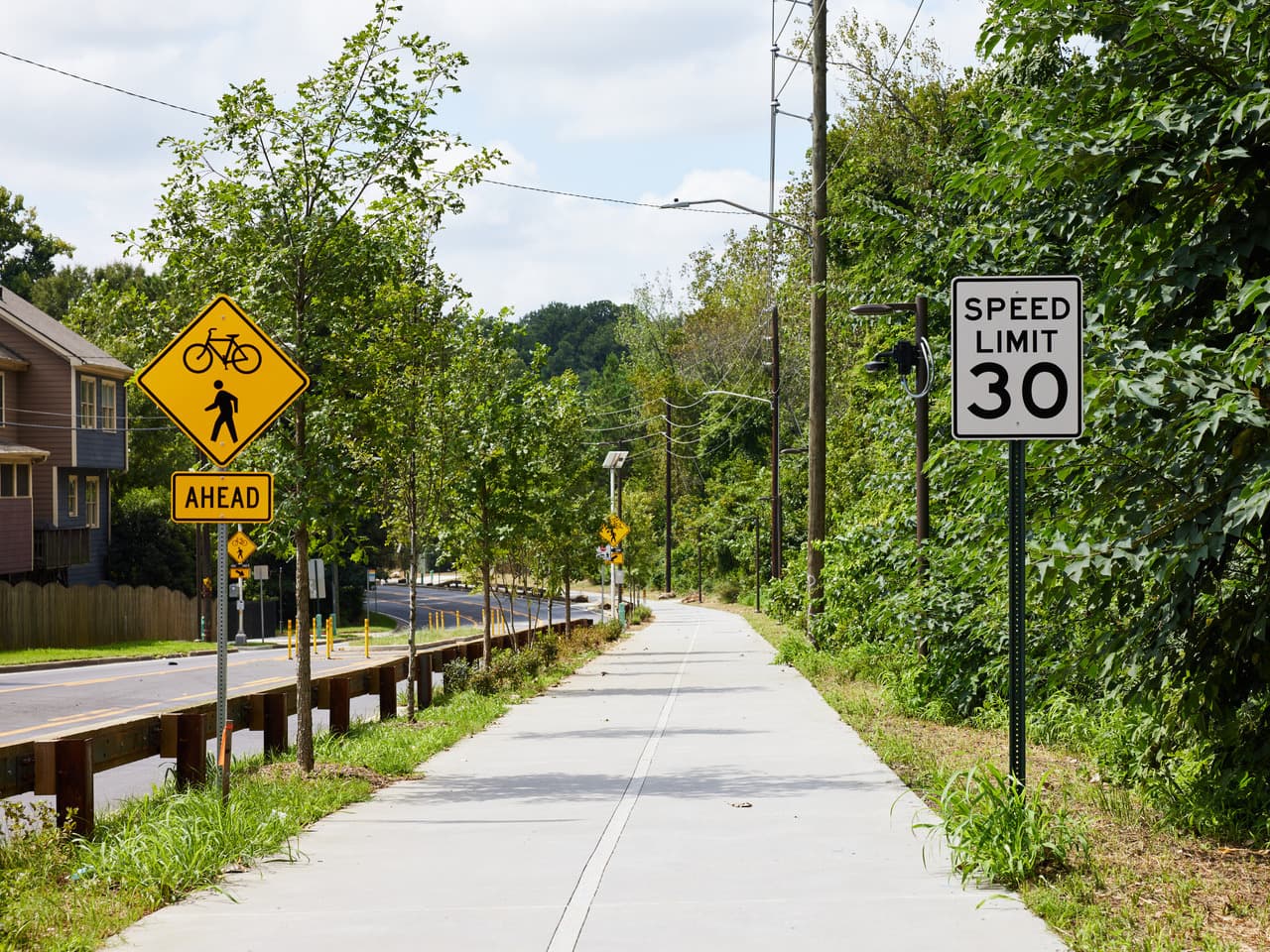 A pathway runs alongside a road and a line of trees.