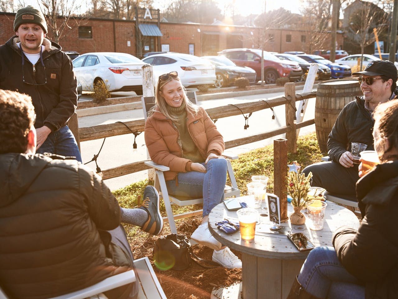 A group of people sit around an outdoor table laughing.