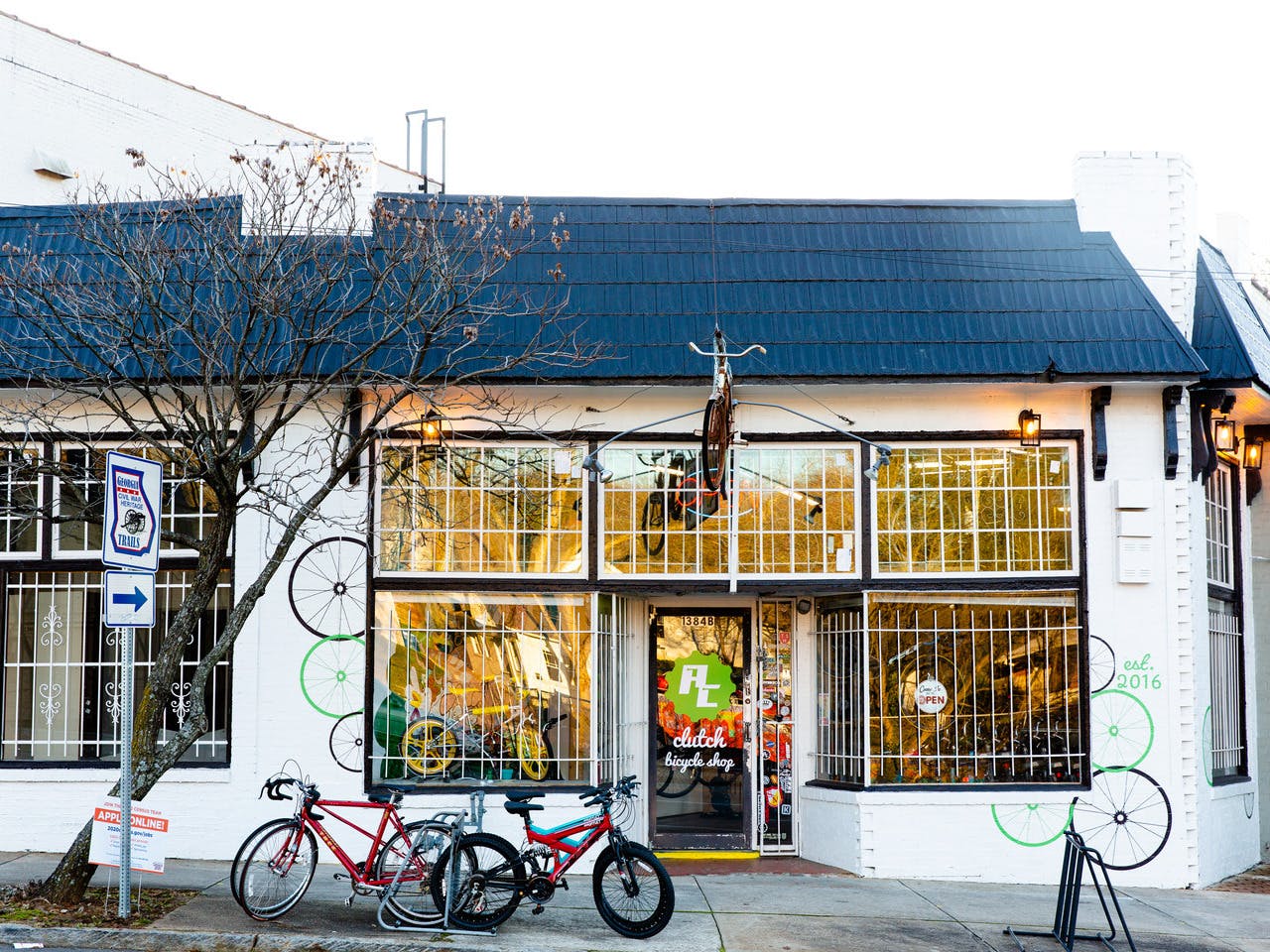 A bright white building with a lot of windows has colorful bike murals painted on the exterior and bikes lined nicely outside.