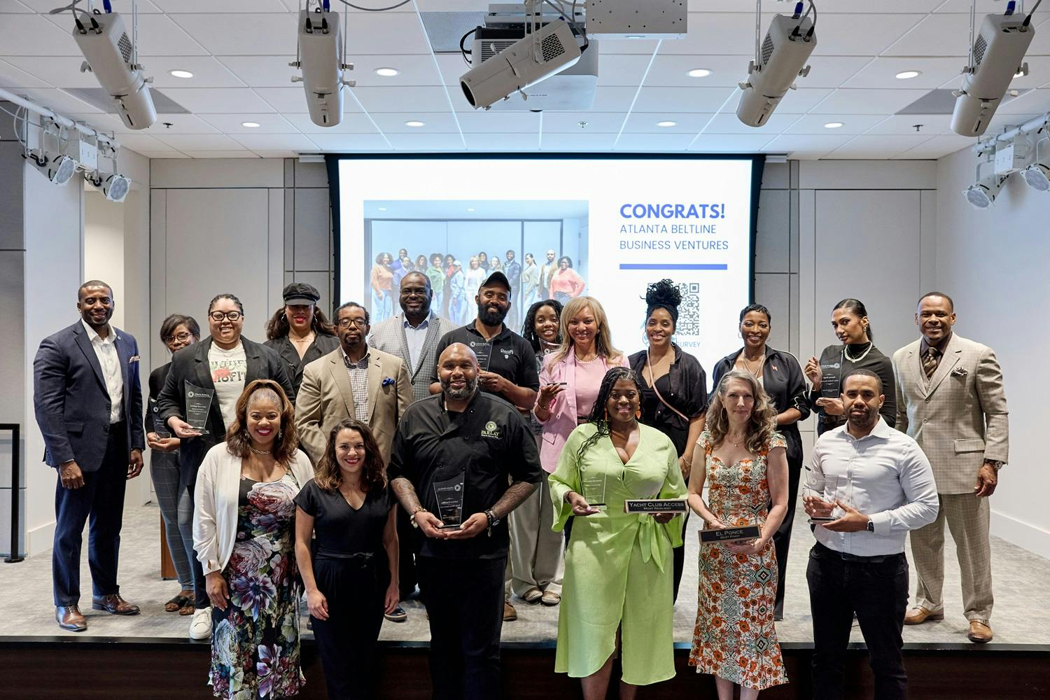 A group of Atlanta business owners stands on stage as the second graduating cohort of Beltline Business Ventures. (Photo Credit: Erin Sintos)