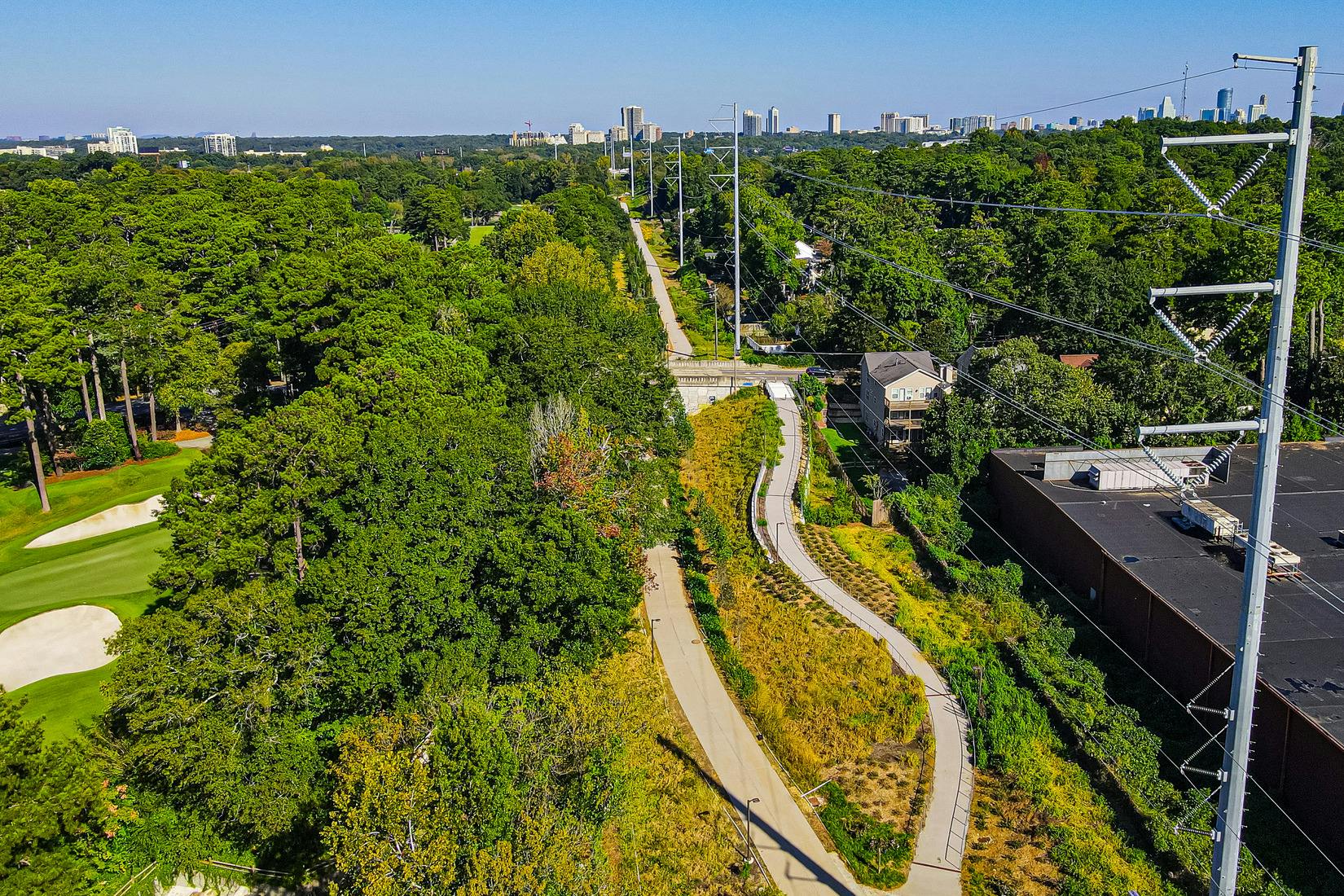 The Beltline's Northeast Trail winds through greenery by Ansley Mall with the Atlanta skyline in the distance. (Photo Credit: LoKnows Drones)