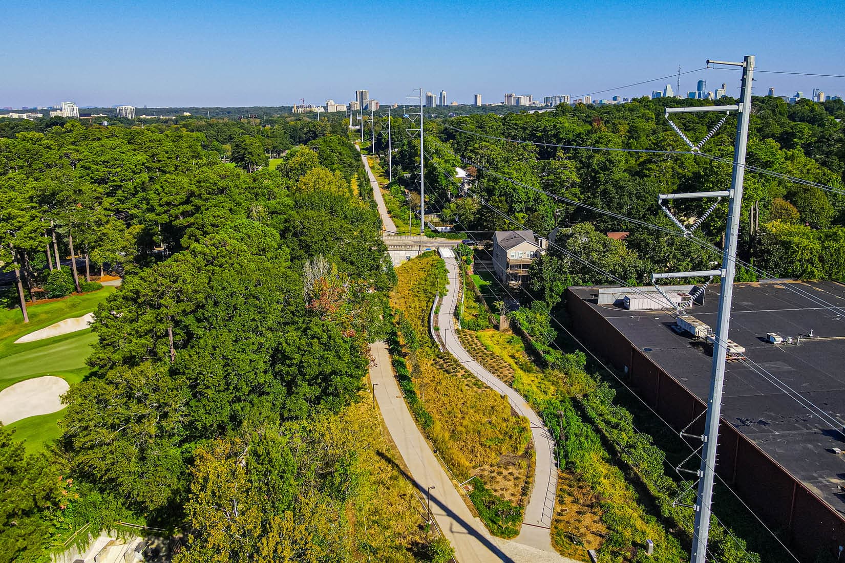 The Beltline's Northeast Trail winds through greenery by Ansley Mall with the Atlanta skyline in the distance. (Photo Credit: LoKnows Drones)