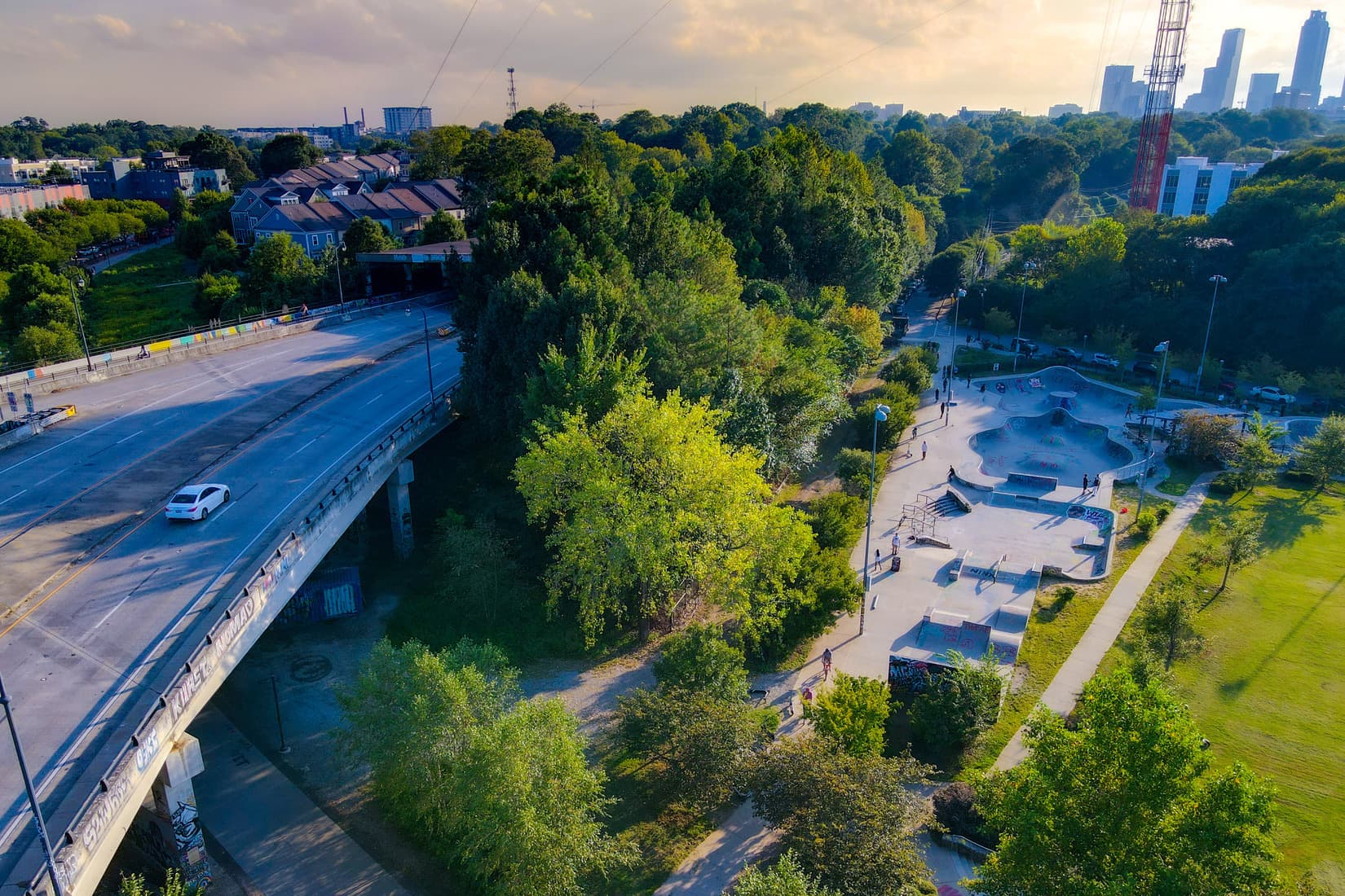 An aerial view of a park showcasing a lush green grass field next to a skatepark.