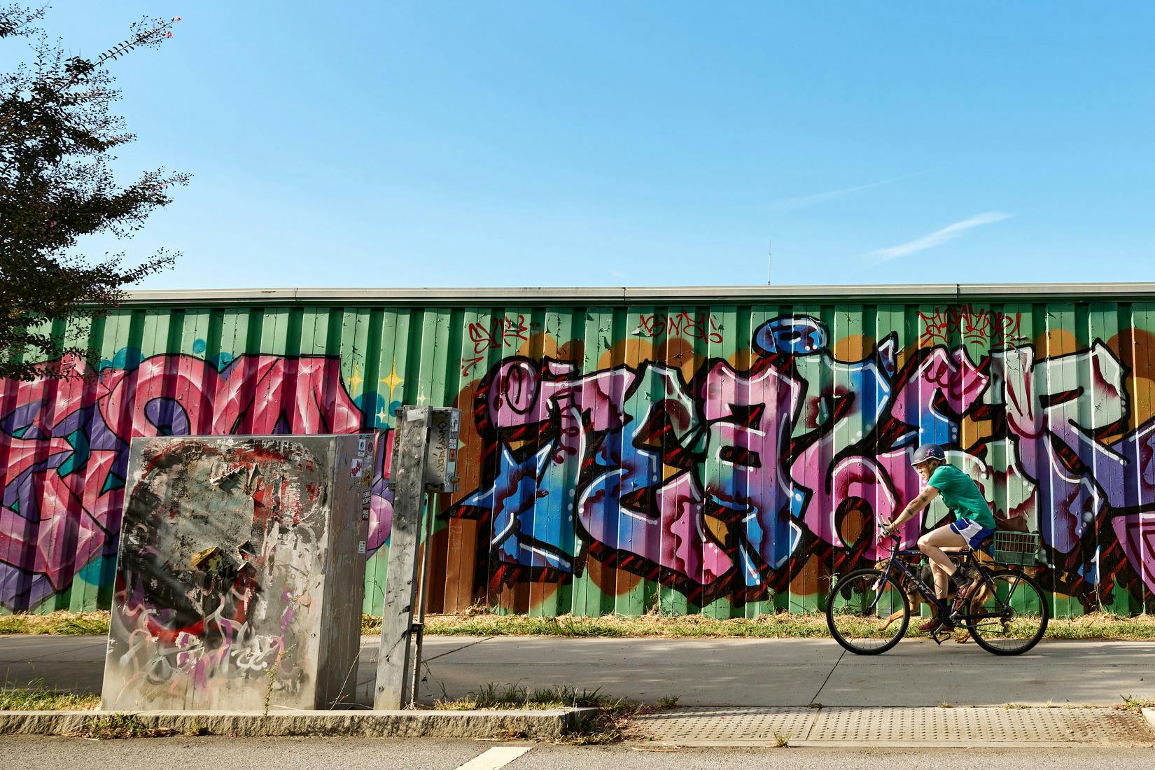 A person bikes past a mural.