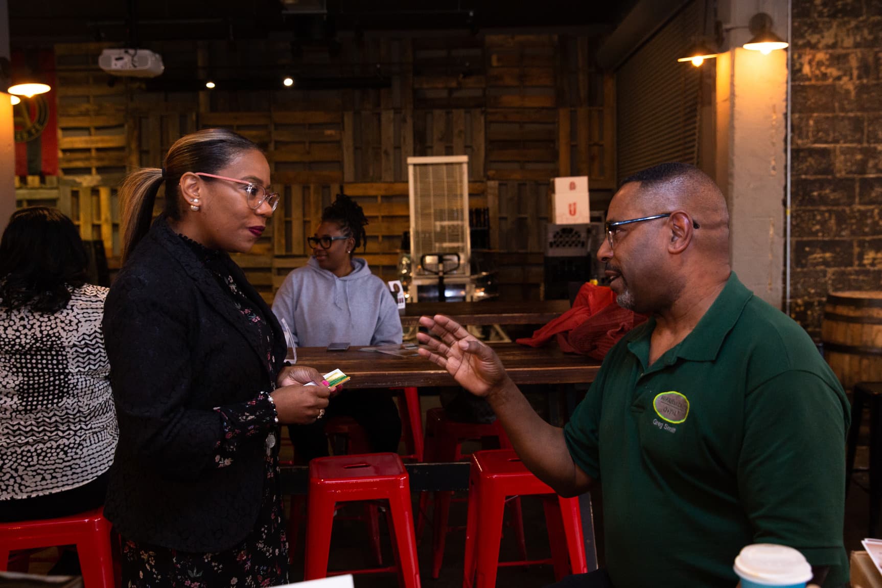 Two people dressed in business casual attire talk attentively to each other.