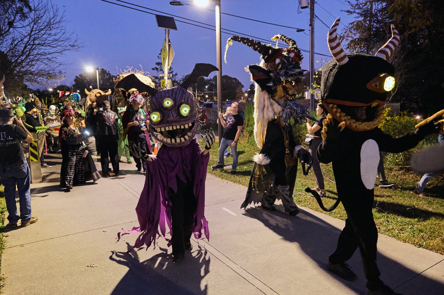 People dressed in elaborate "monster" costumes walk down the Beltline trail at dusk.