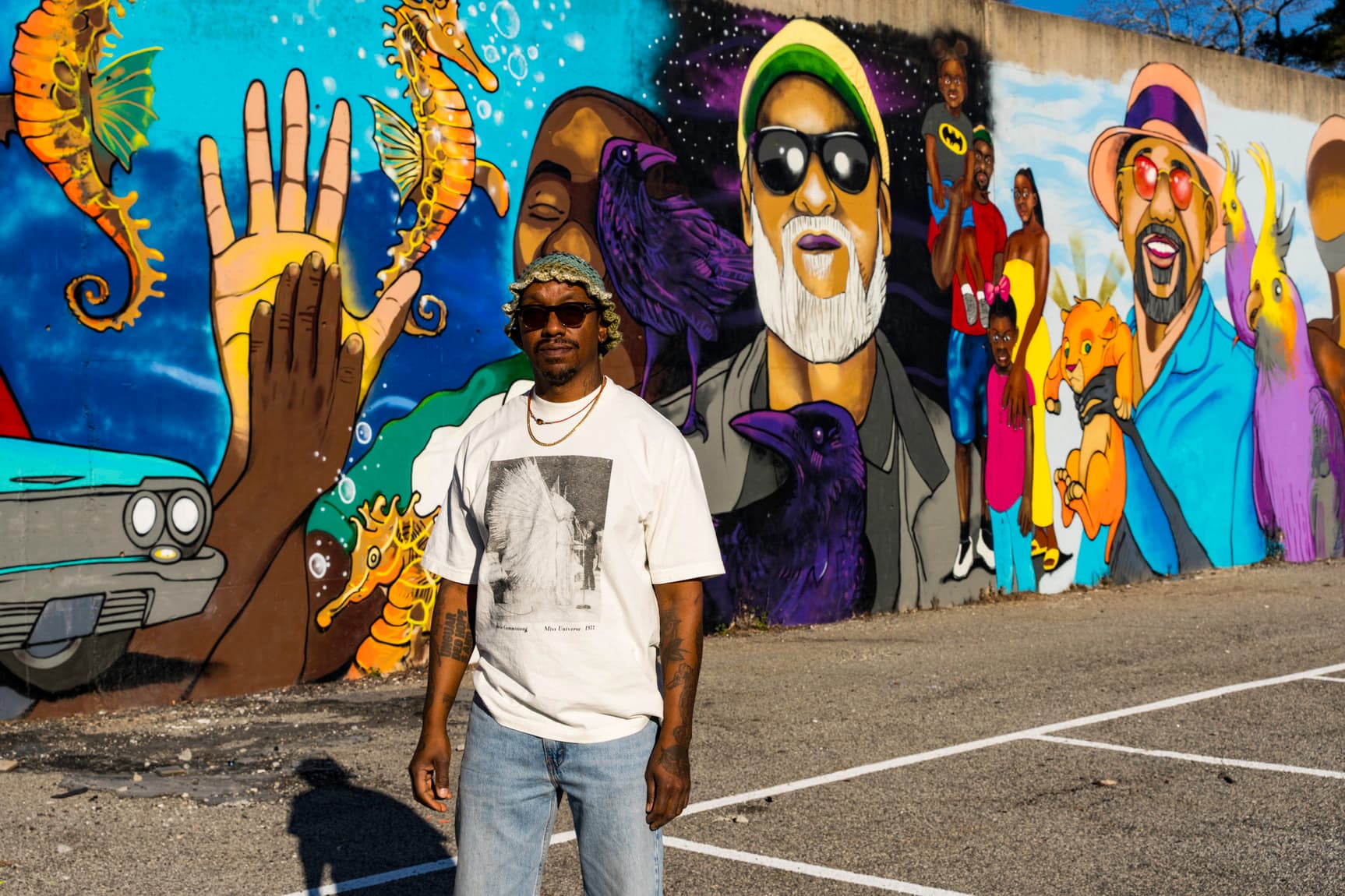 A man stands in front of a colorful mural that depicts several different fathers.