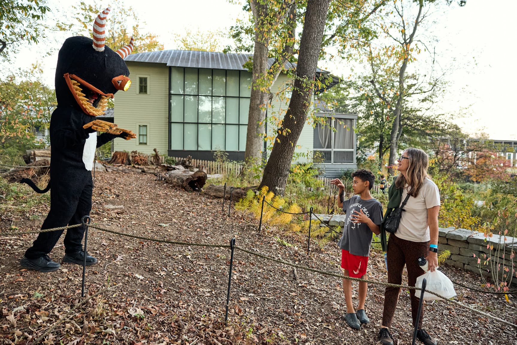 An adult and a young child stand, looking in awe at a cardboard creature.