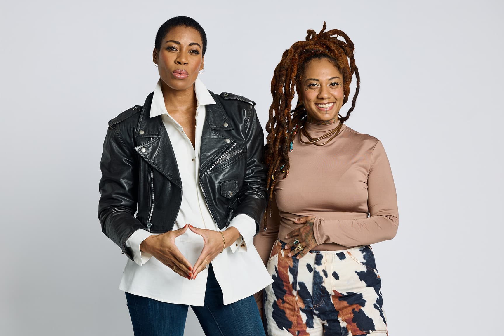 Two people stand next to each other, posing in front of a white background.