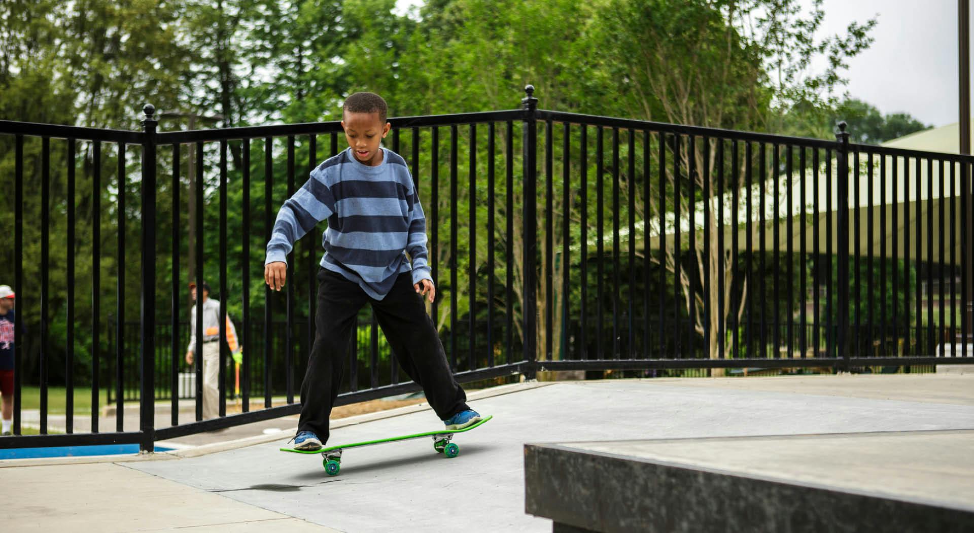A young boy skateboards down a small ramp.
