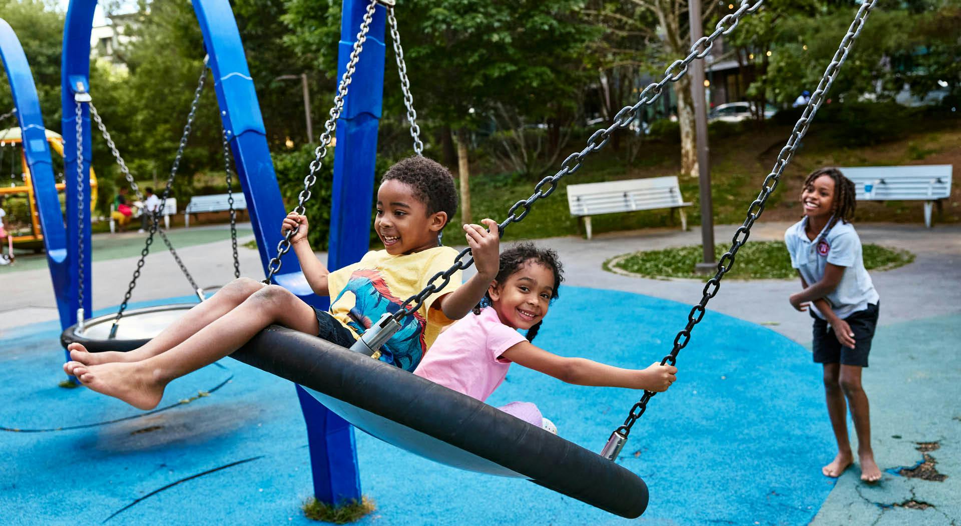 Two kids swing on a platform swing at Historic Fourth Ward Park. (Photo Credit: Erin Sintos)