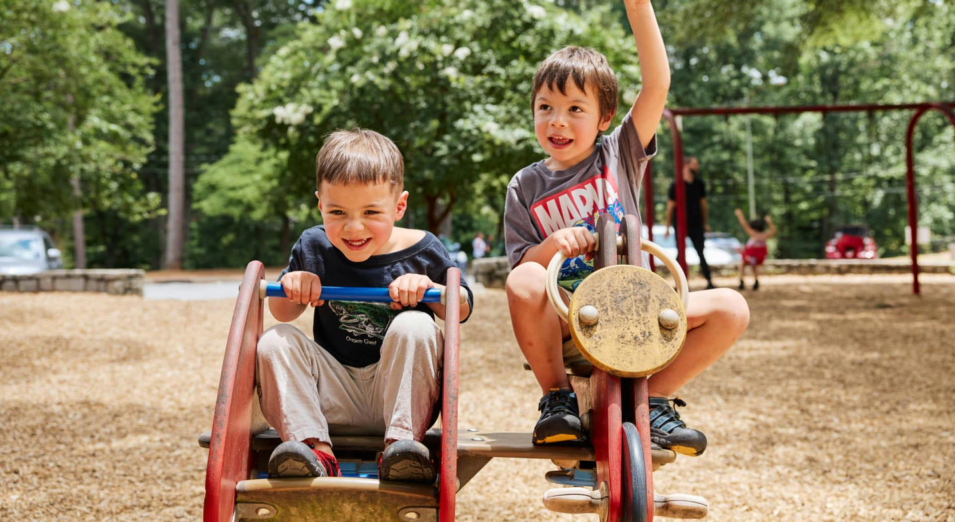Two young boys ride on playground equipment at Perkerson Park. (Photo Credit: Erin Sintos)