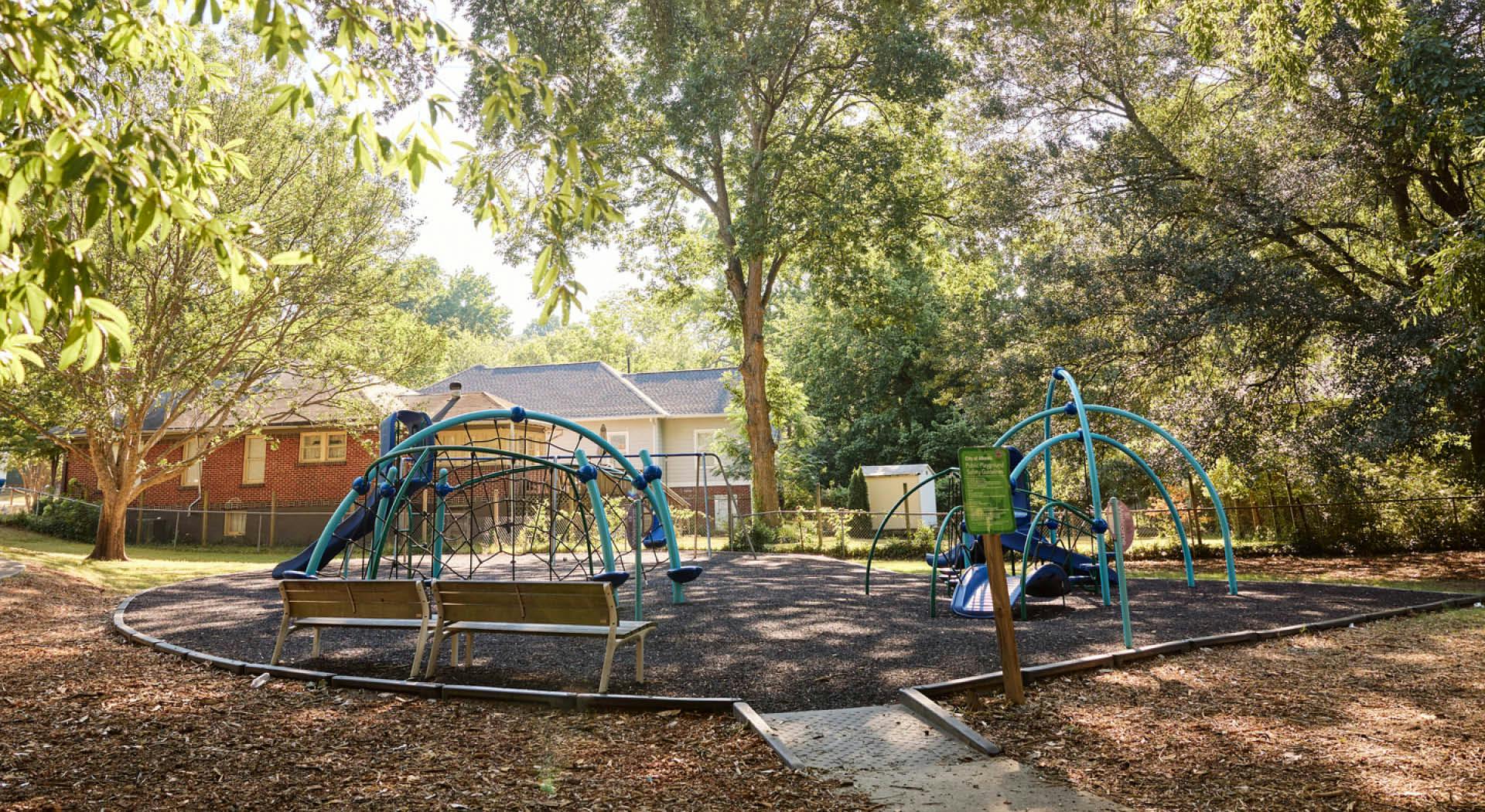 A playground is tucked in Rose Circle Park under a lush tree canopy. (Photo Credit: Erin Sintos)