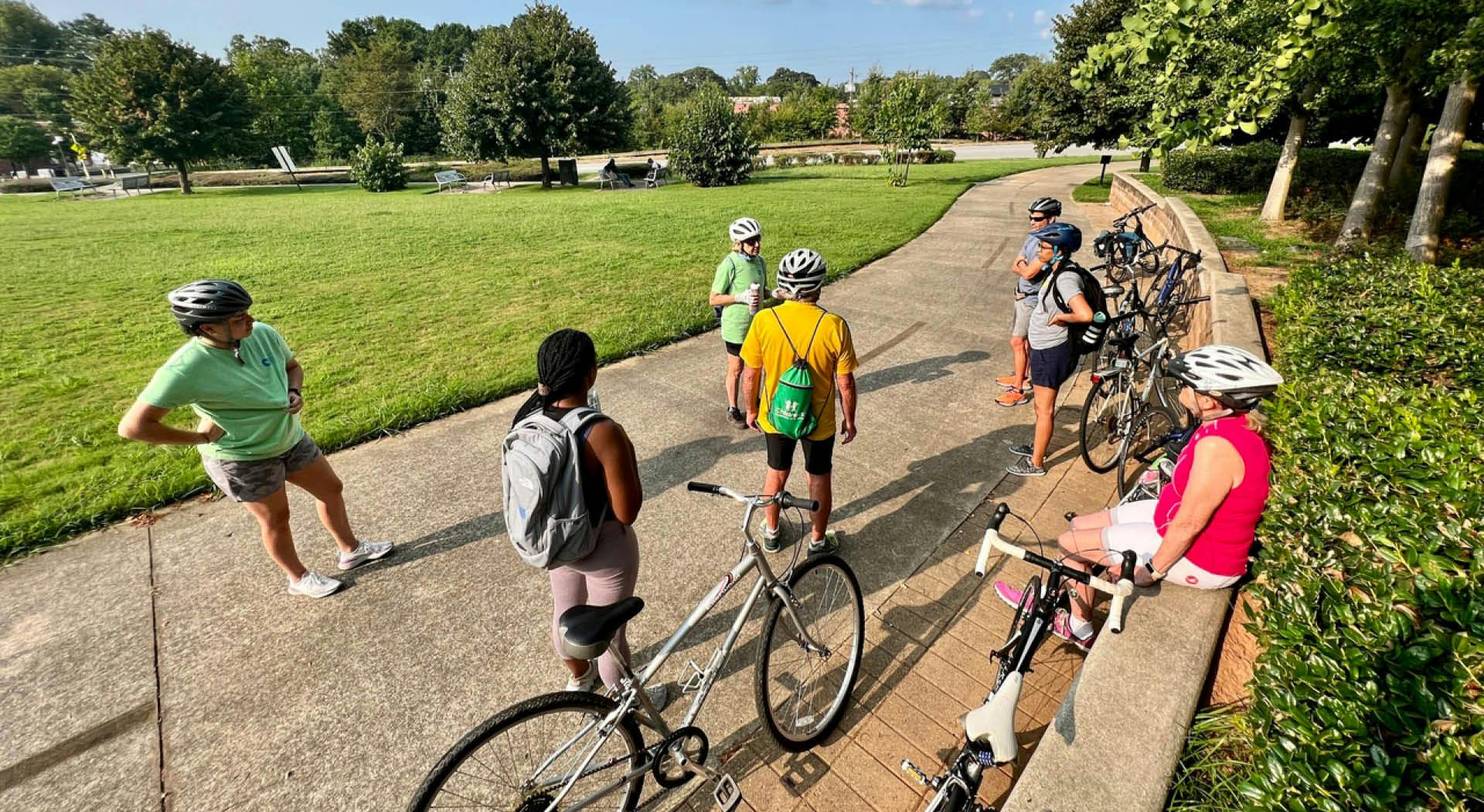 A group of people on a bike tour take a break in Gordon White Park on the West End Trail. (Photo Credit: John Becker)