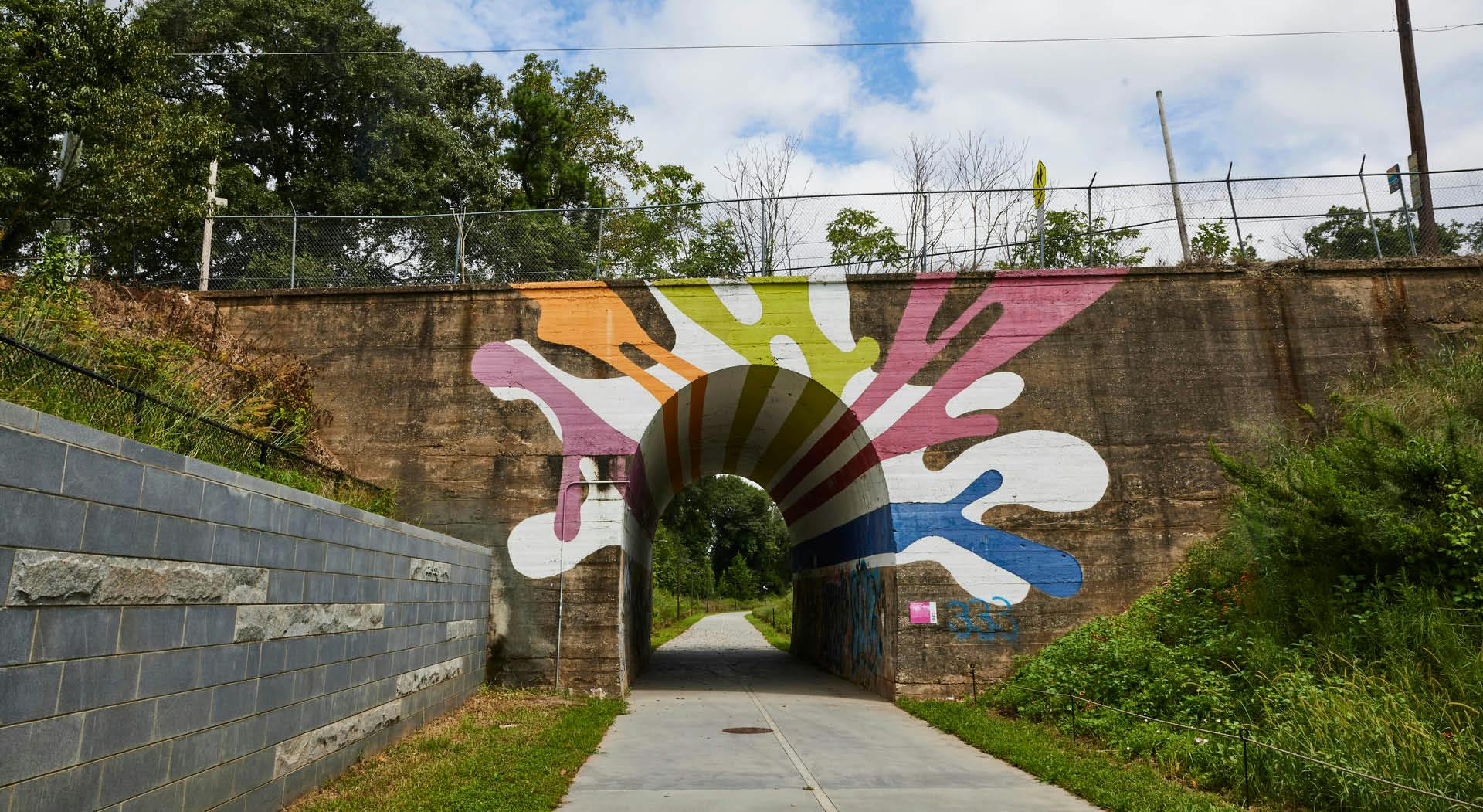 A colorful mural adorns the bottom of a bridge.