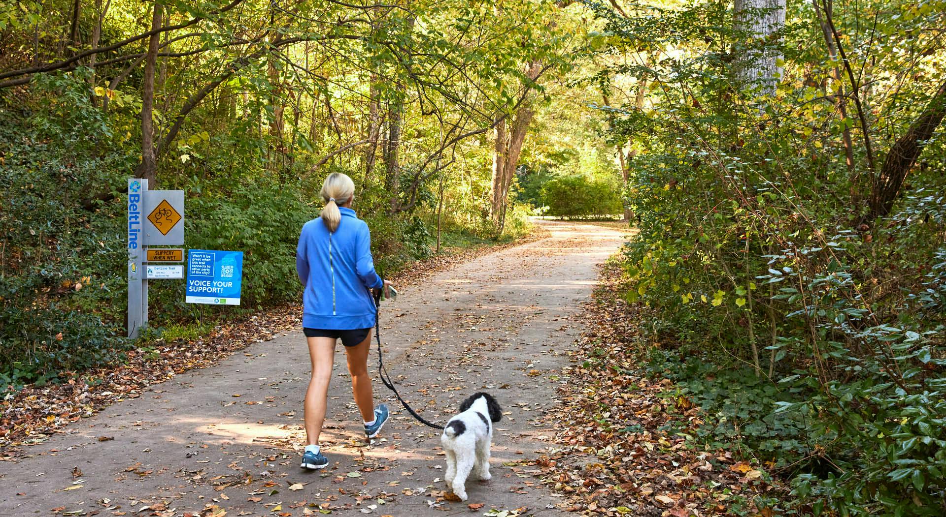 A lady walks her dog on the Beltline's Northside Trail.