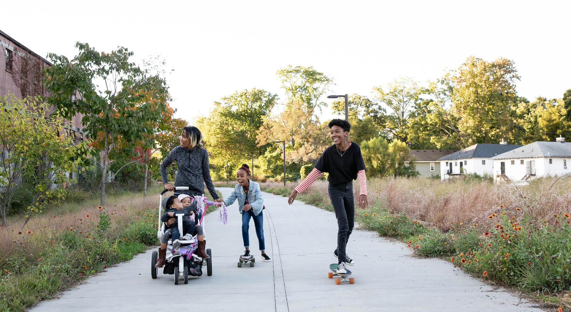 A family with stroller and skateboards rolls down the Southwest Trail.