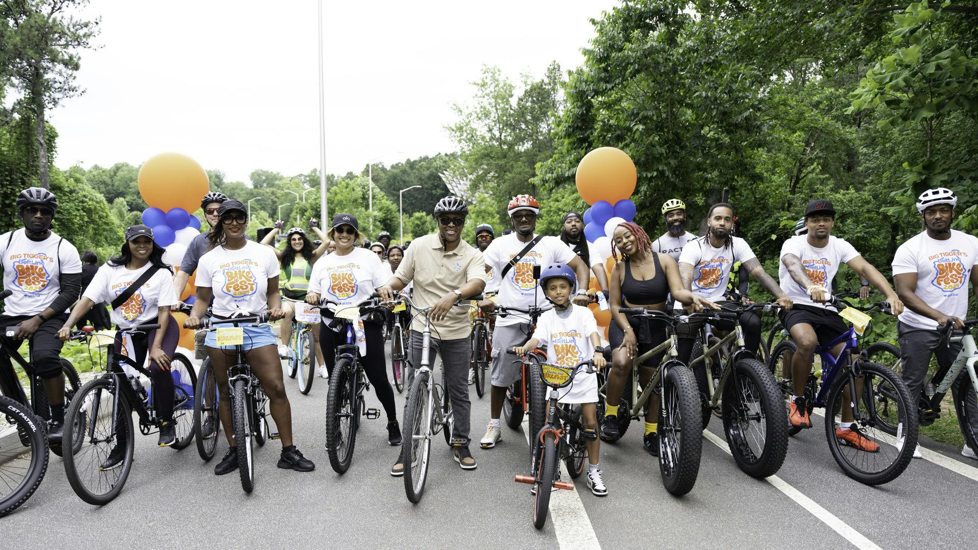A group of people stand on their bikes smiling and ready to ride.