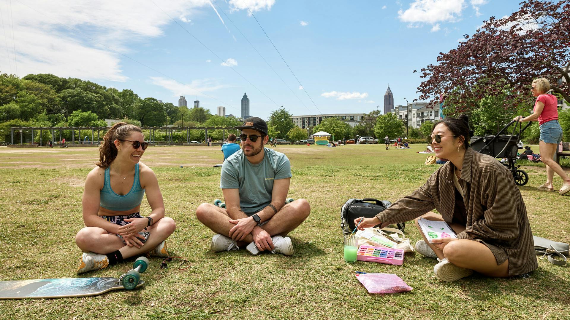 Three people sitting on the grass in a park, enjoying a sunny day together.