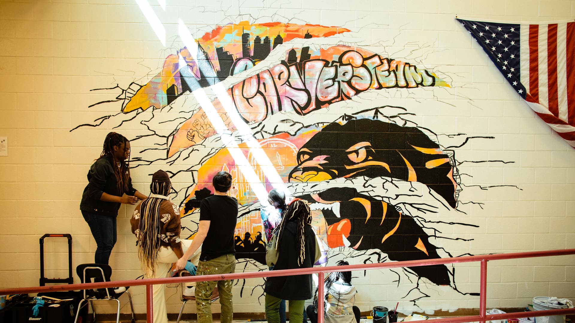 Students work on a mural inside of their school.