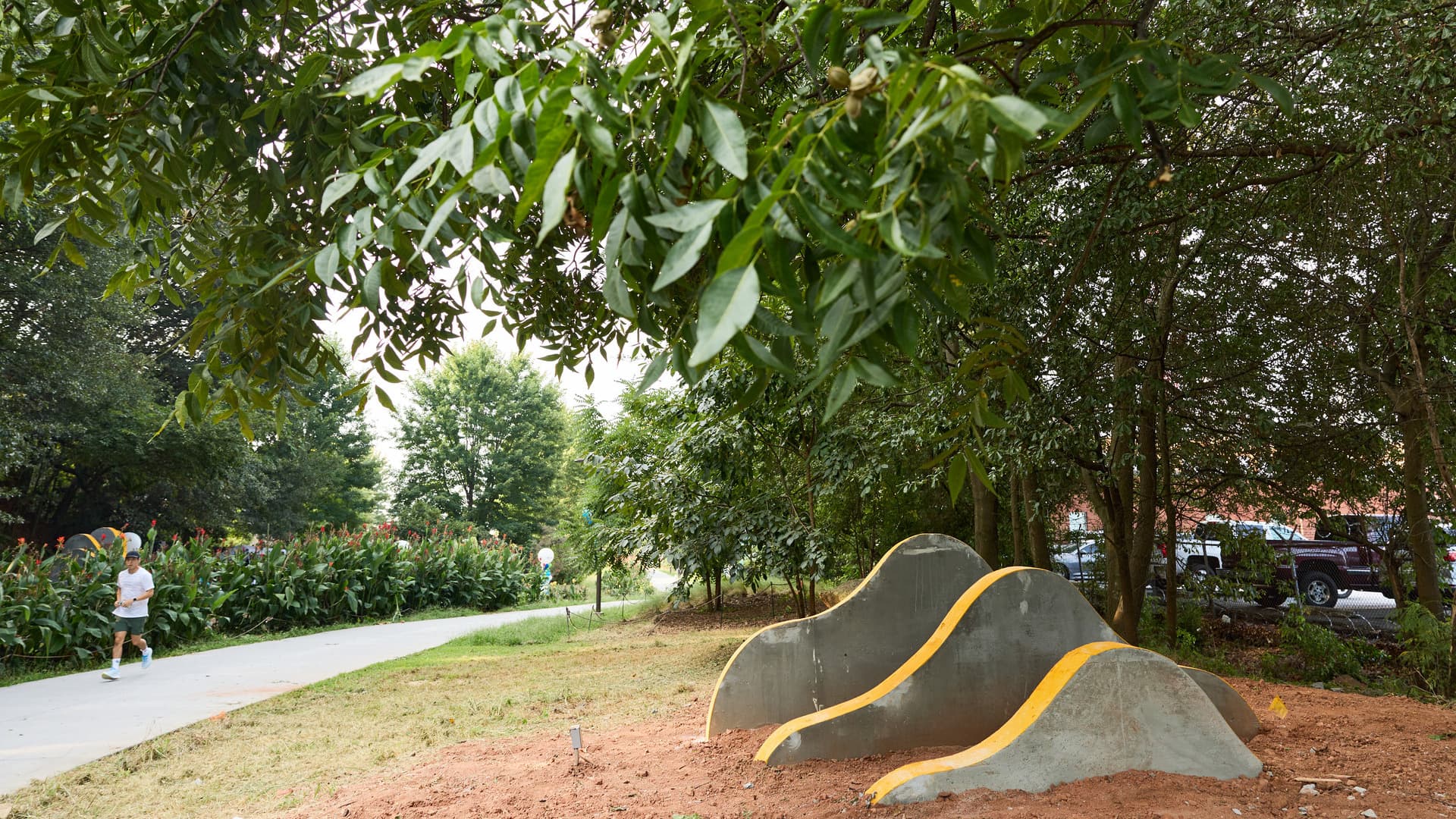A sculpture of rolling concrete pieces sits to the right of a walking path.