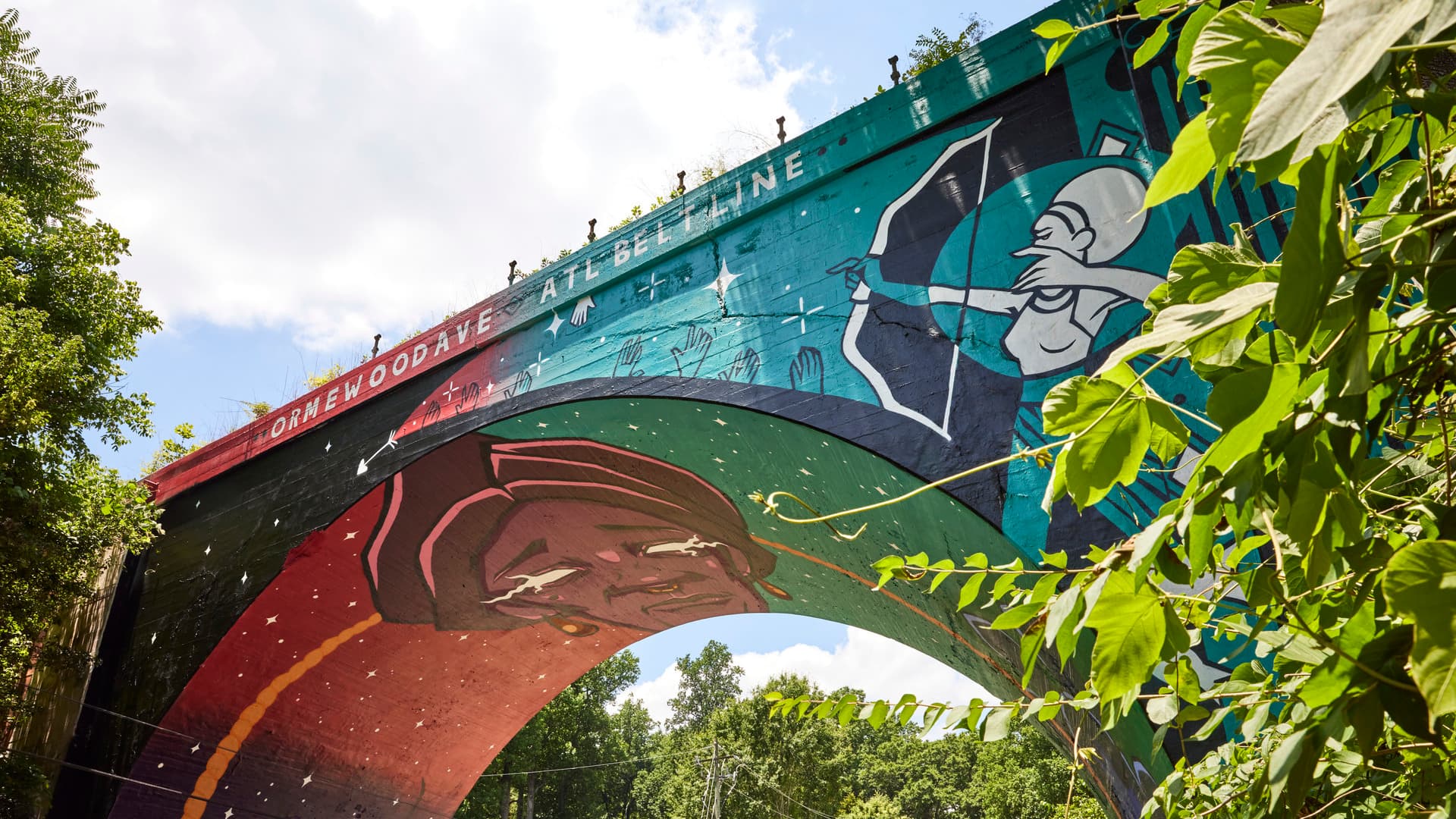 A colorful mural adorns the bottom of a bridge.