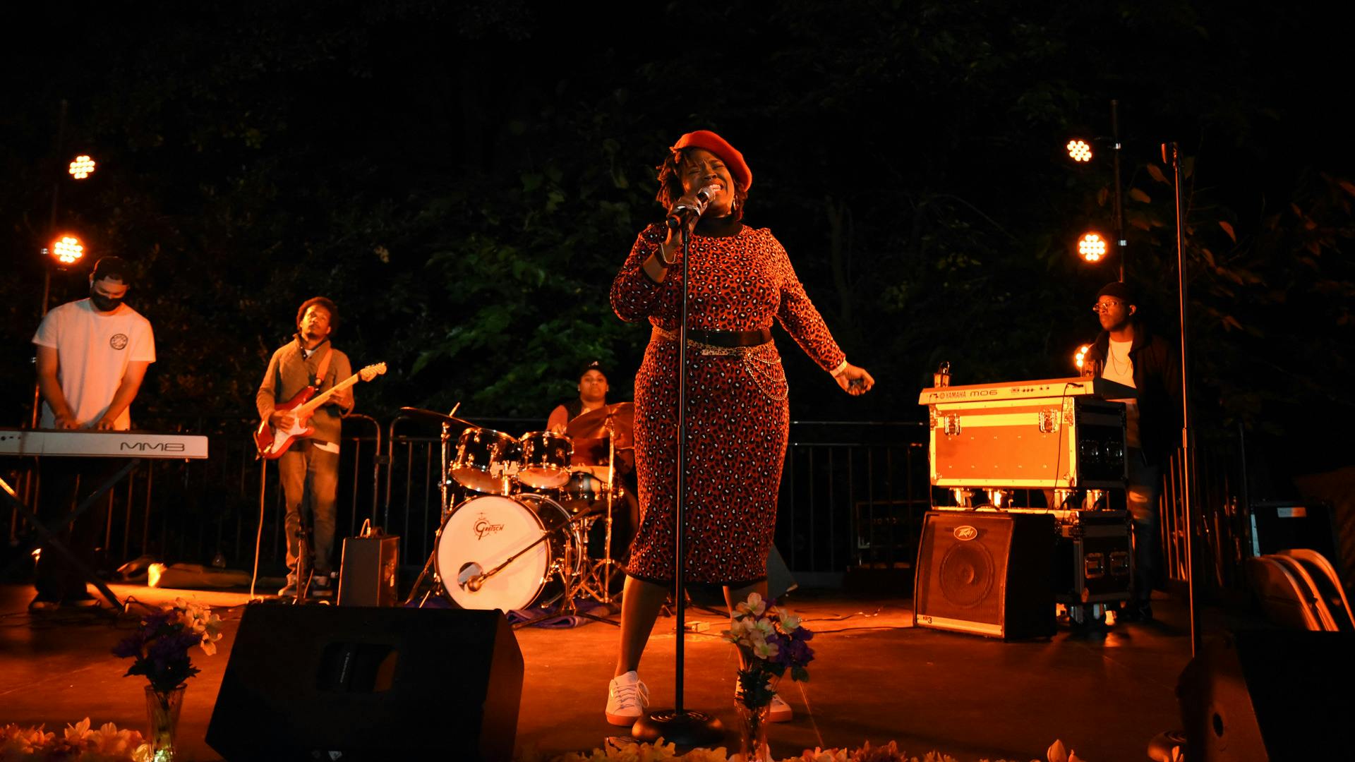 A woman stands in front of a live band and sings.
