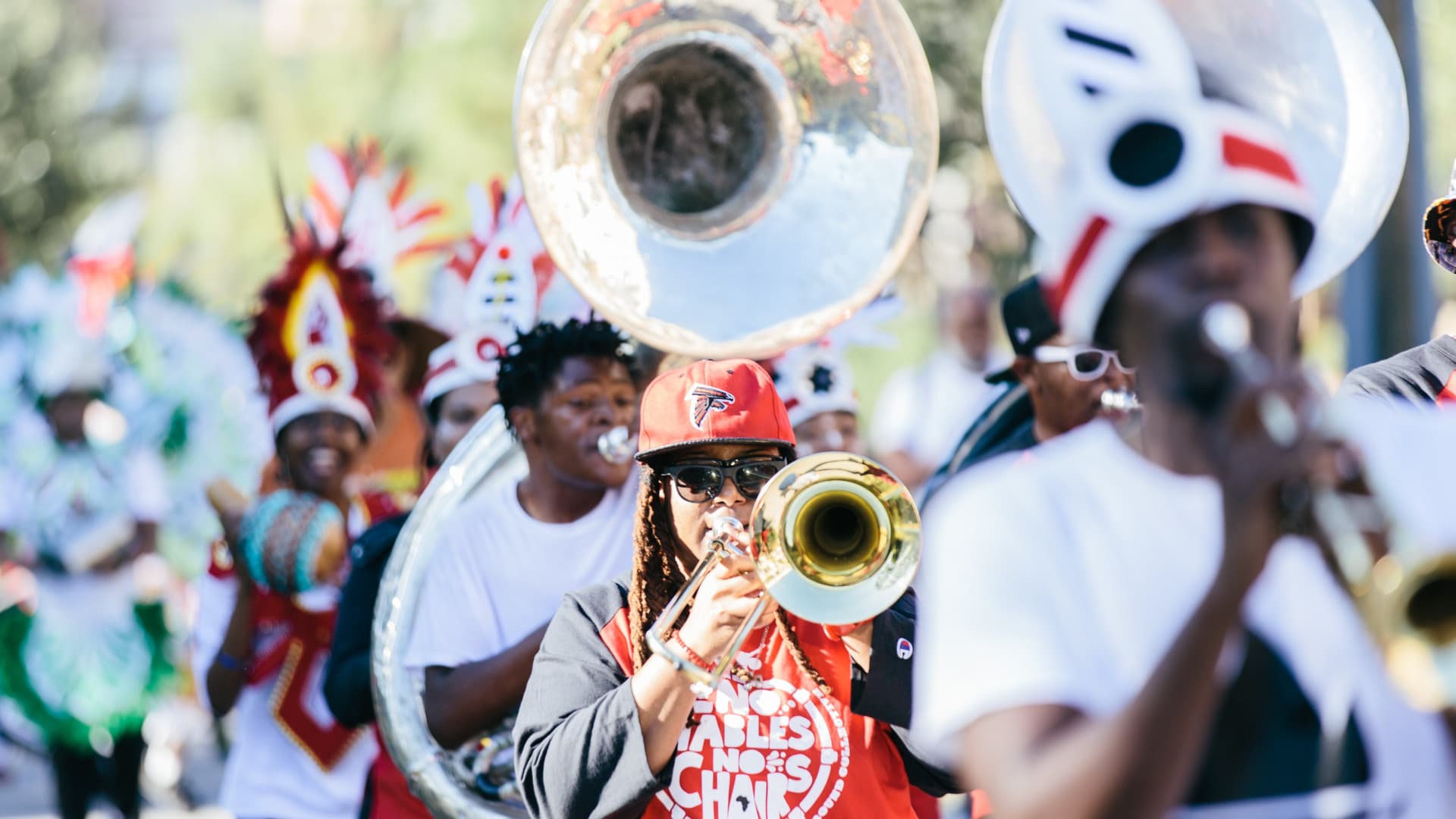 People walk playing trumpets and tubas.