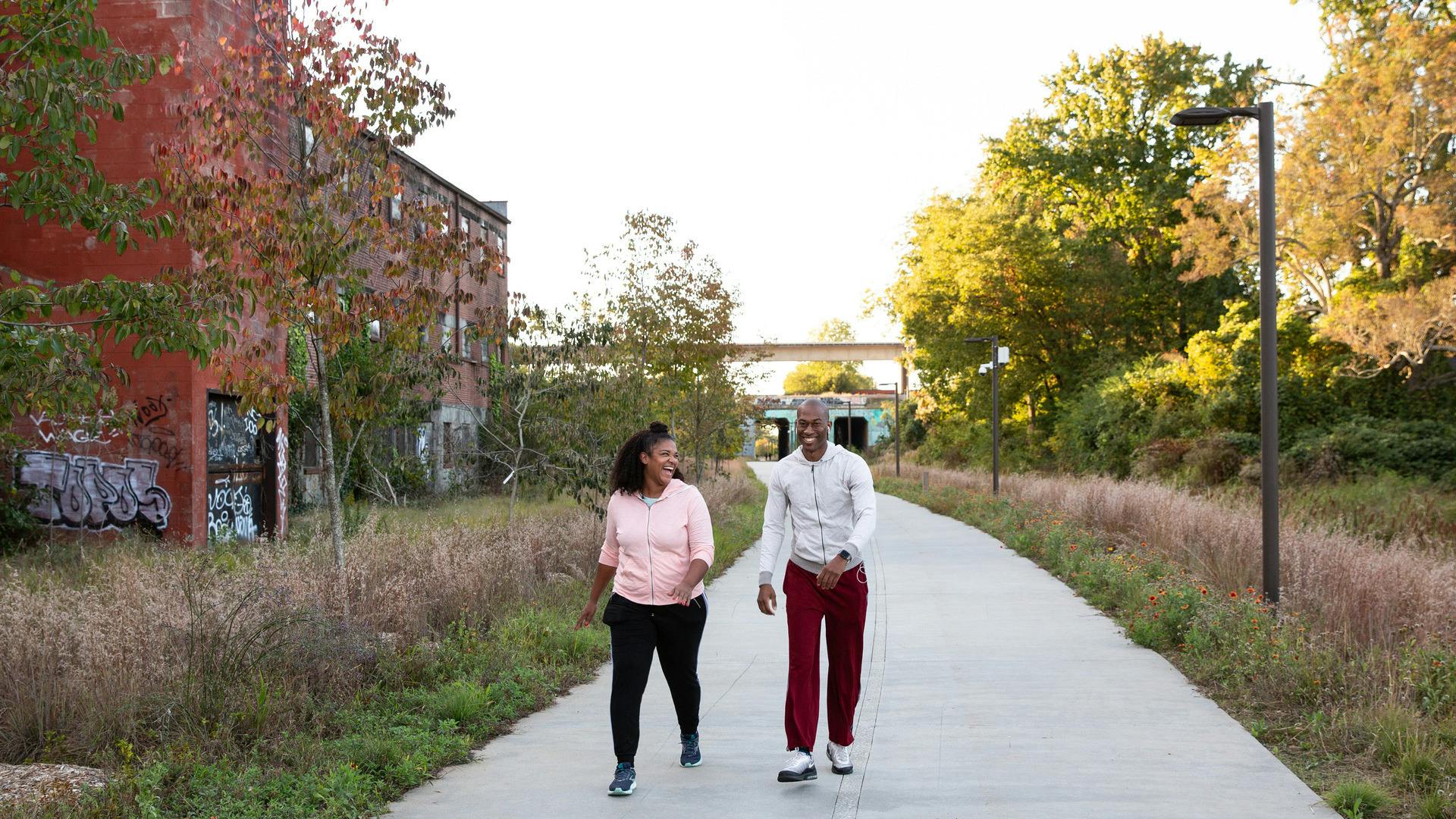 A couple laughs while walking along a paved path.