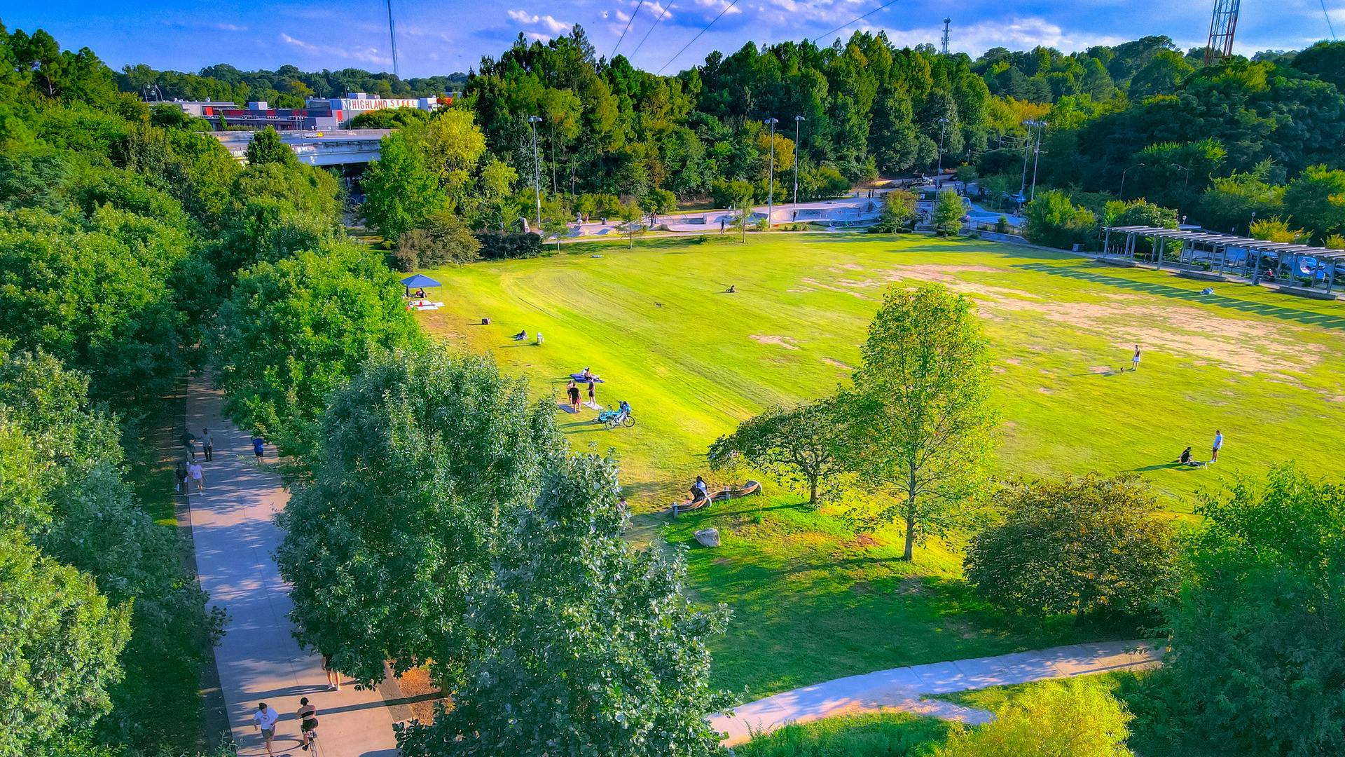 An aerial view of a park showcasing a lush green grass field next to a skatepark.