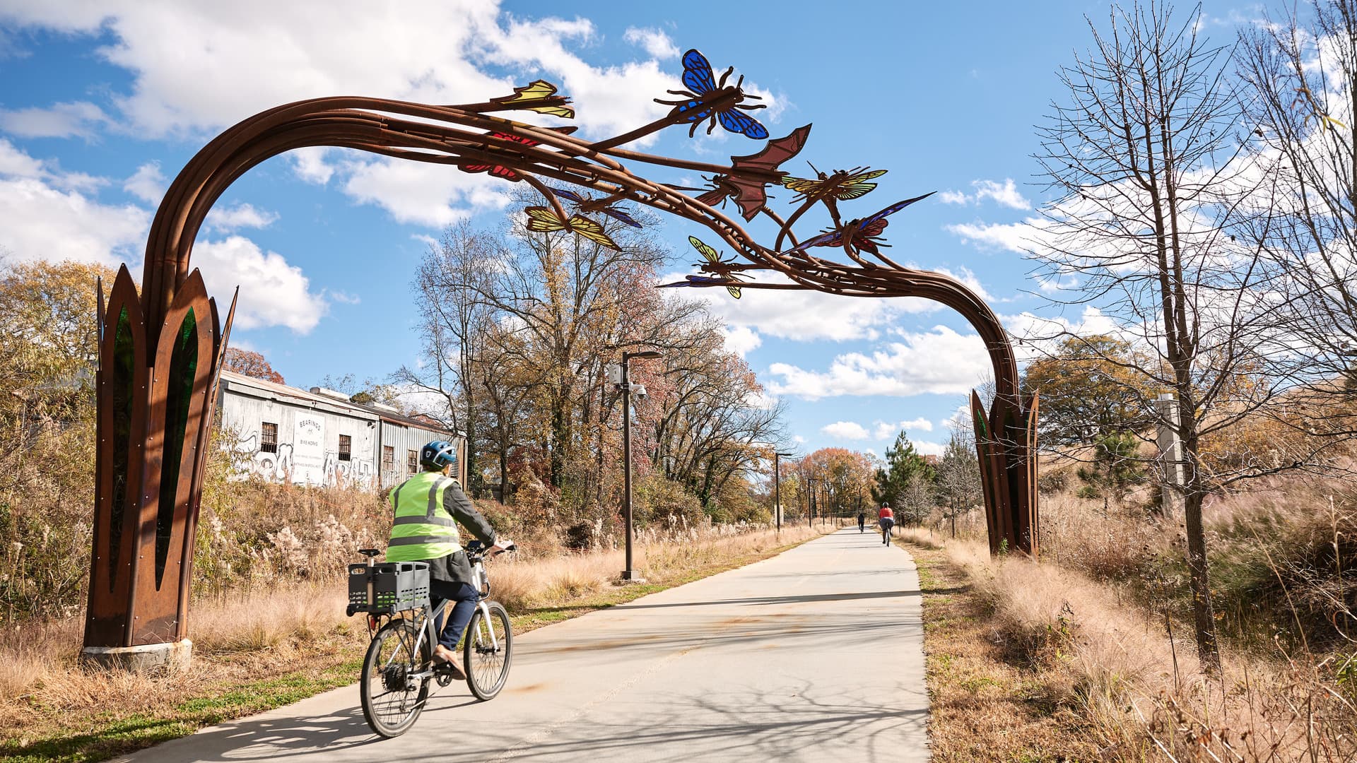 A man bikes under a sculpture that features several larger-than-life butterflies.