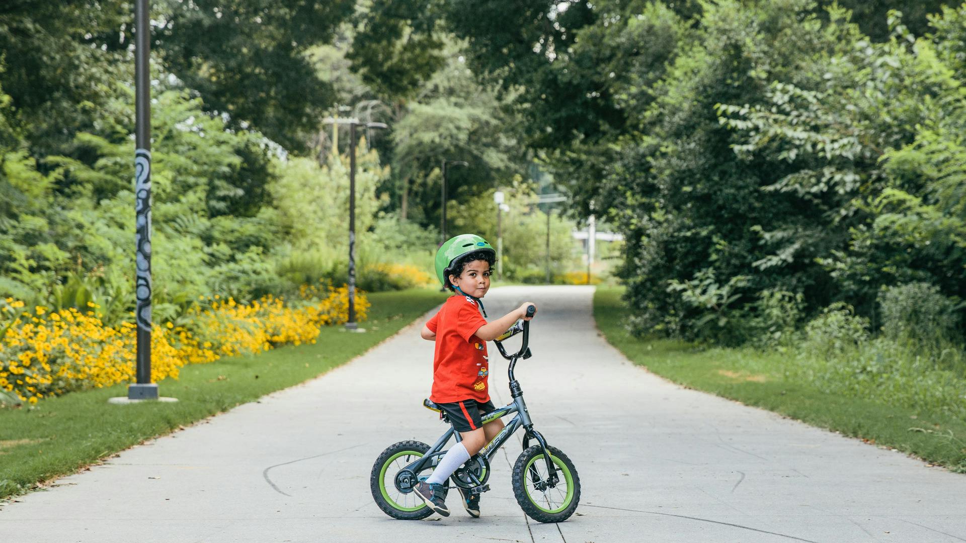 A kid sits on his bike, smiling.