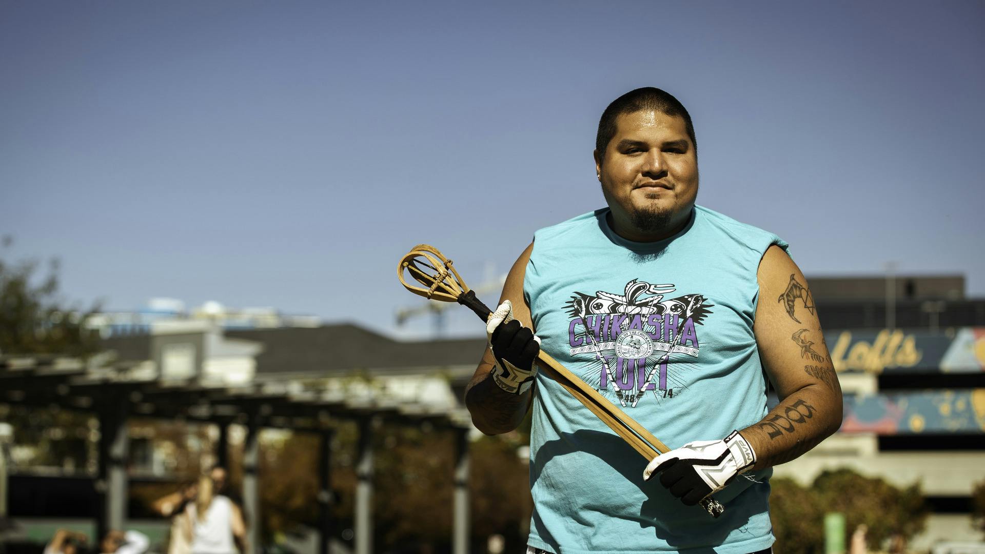 A person stands, holding a toli stick and smiling for the camera.