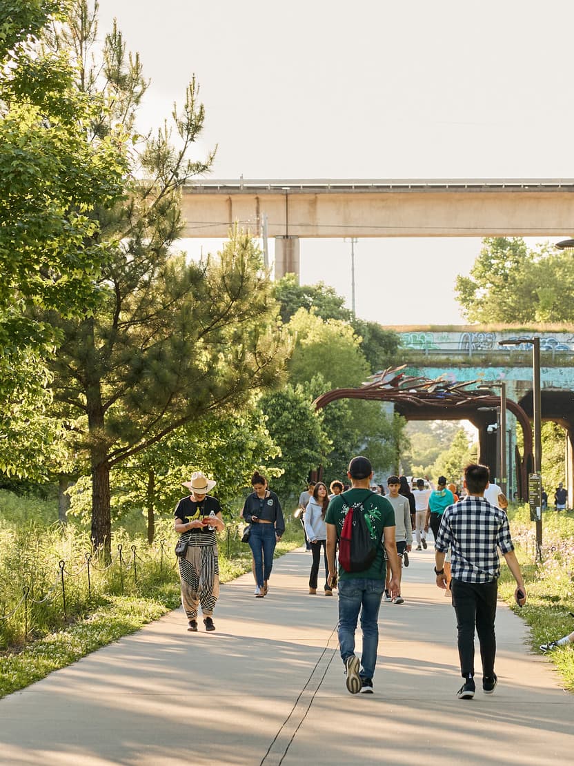 People walk along a trail surrounded by greenery.