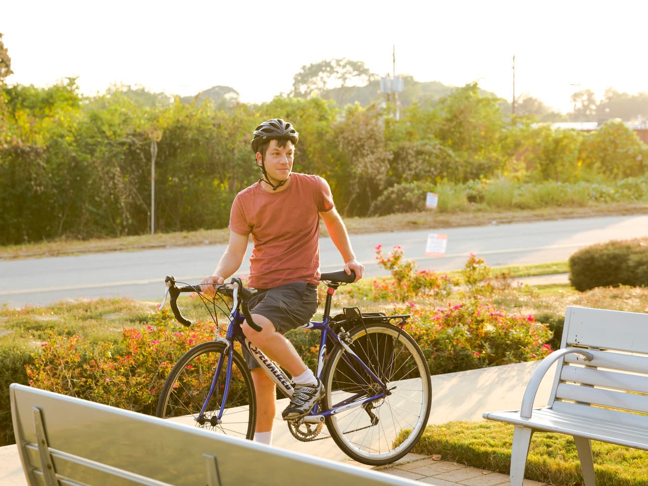 A man stands on his bike at a park.