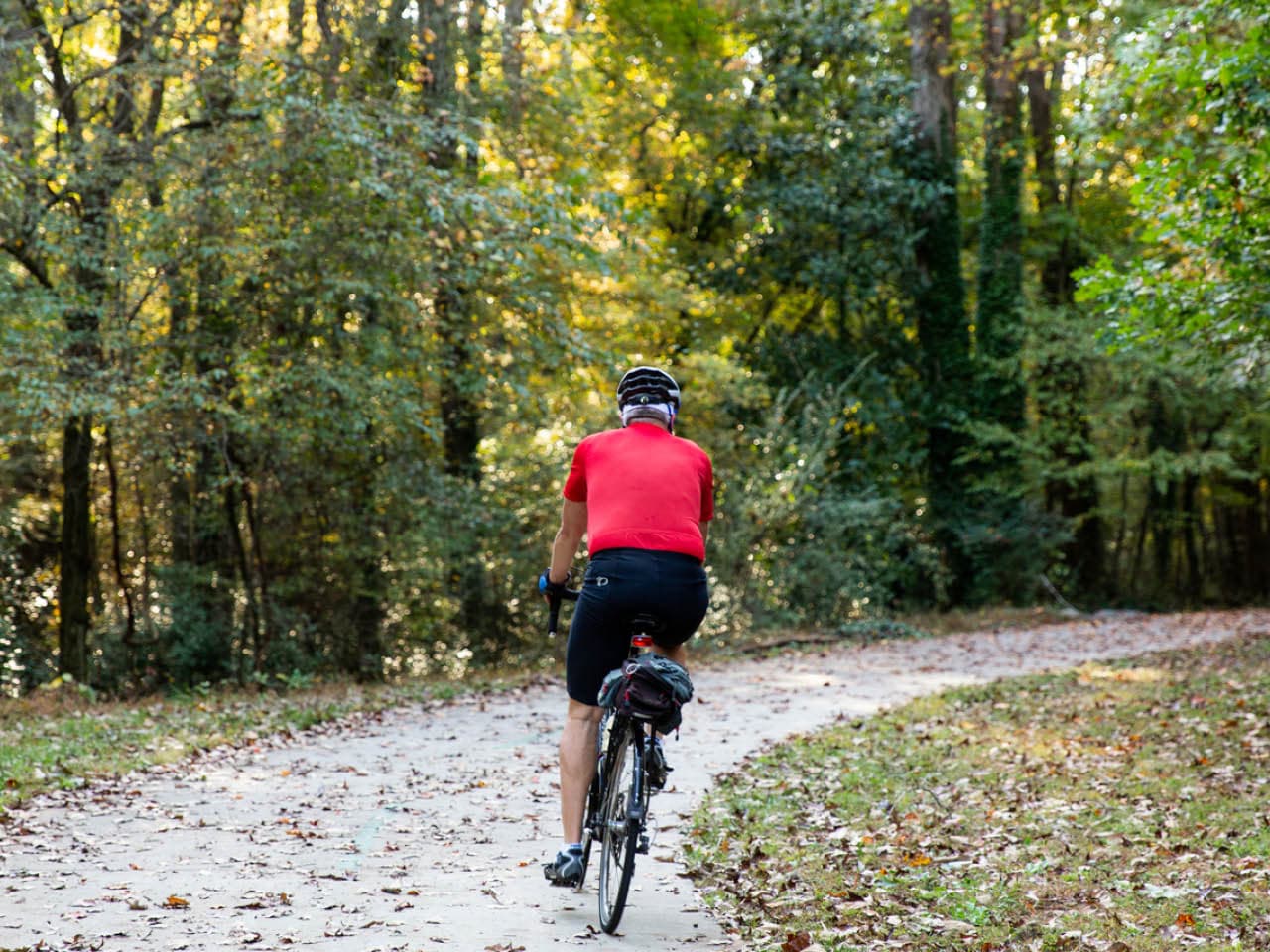 A cyclist rides around a bend through the woods on the Southwest Connector Trail (Photo Credit: Erin Sintos)